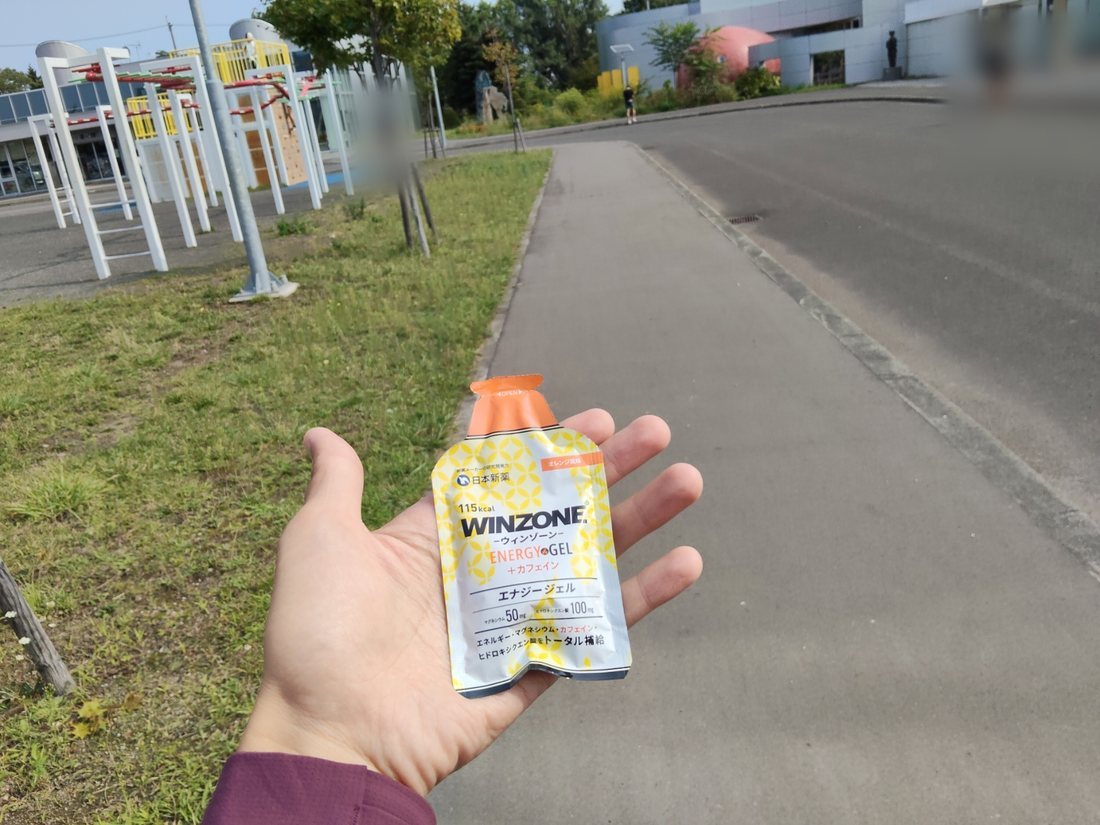 レース会場でウィンゾーン エナジージェル オレンジ風味を手に持ったところ